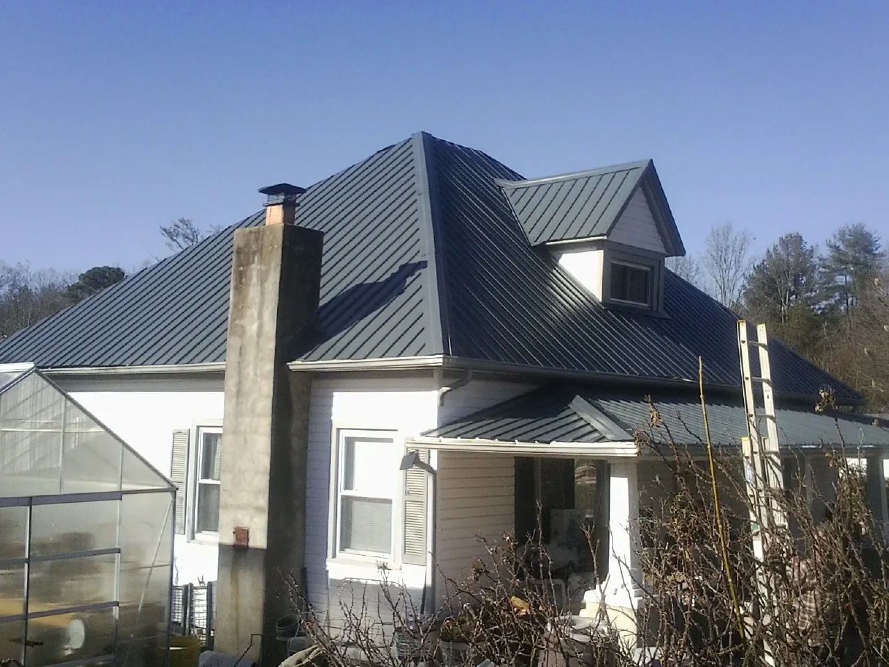 Dark blue standing seam metal roof on a white farmhouse with dormer — Slate & Tile Roof Repair by Roofing Brothers in Cochranville