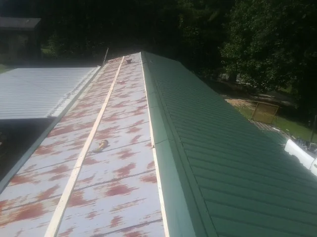 Old rusted panels beside newly installed green metal roofing — Wind Damage Roof Repair by Roofing Brothers in Cochranville