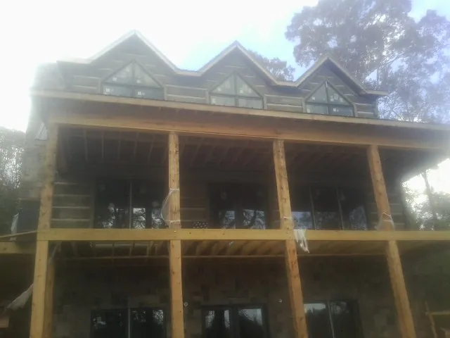 Dormers and porch framing on a large log home under construction — Roof Coating work by our crew in Cochranville