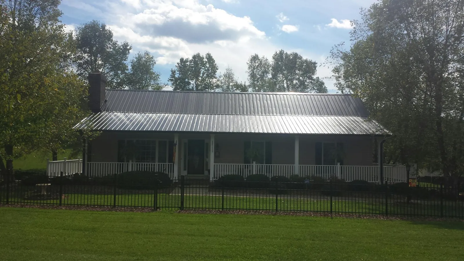Gray metal roof on a brick ranch with a full width front porch — Gutter Guard Installation work by our crew in Cochranville