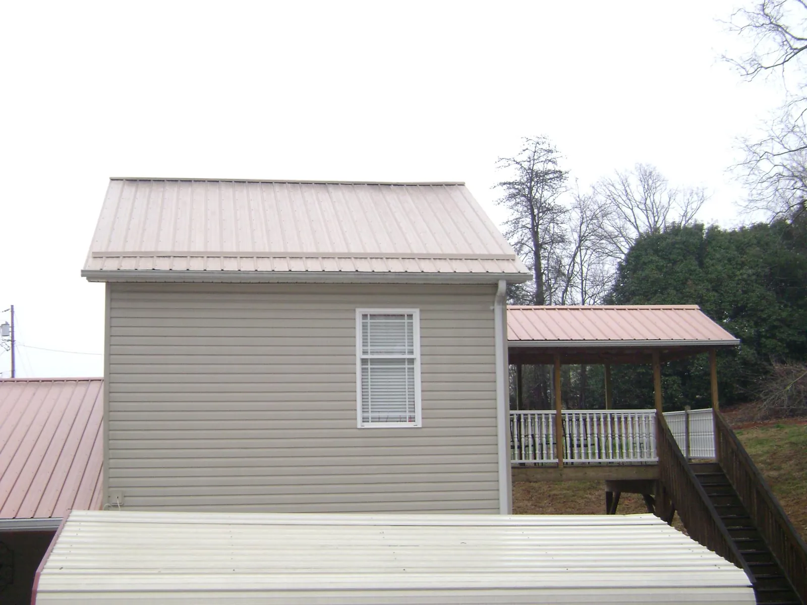 Tan metal roofs on a two story addition and attached porch, from a Roof Replacement job in Cochranville