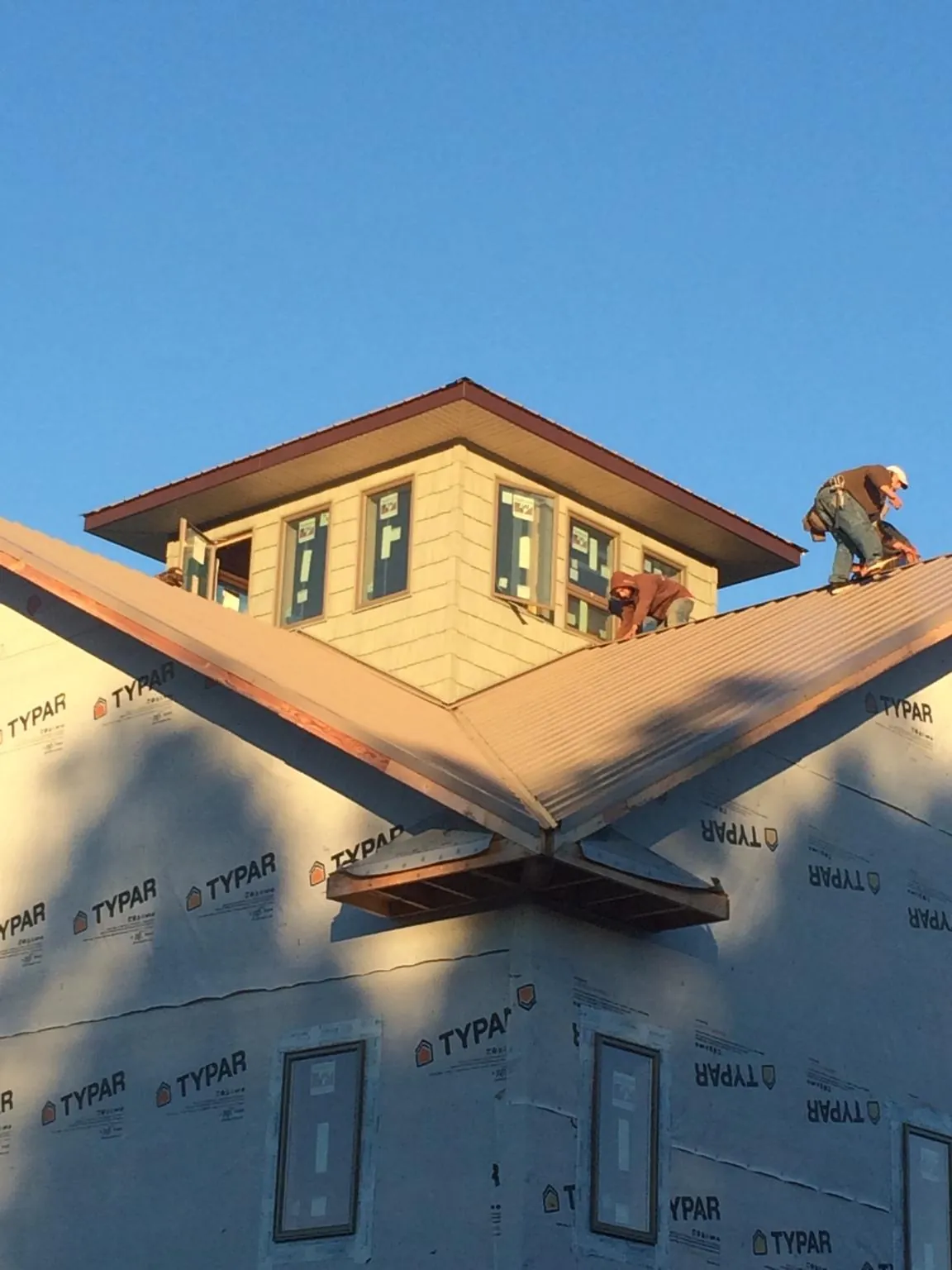 Roofers working around a rooftop cupola on a new metal roof at sunset — Roof Waterproofing in Cochranville by Roofing Brothers